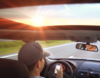 Man driving toward sunset