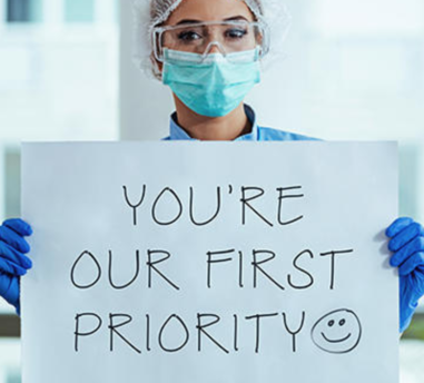 Woman holding sign saying "You're our first priority".